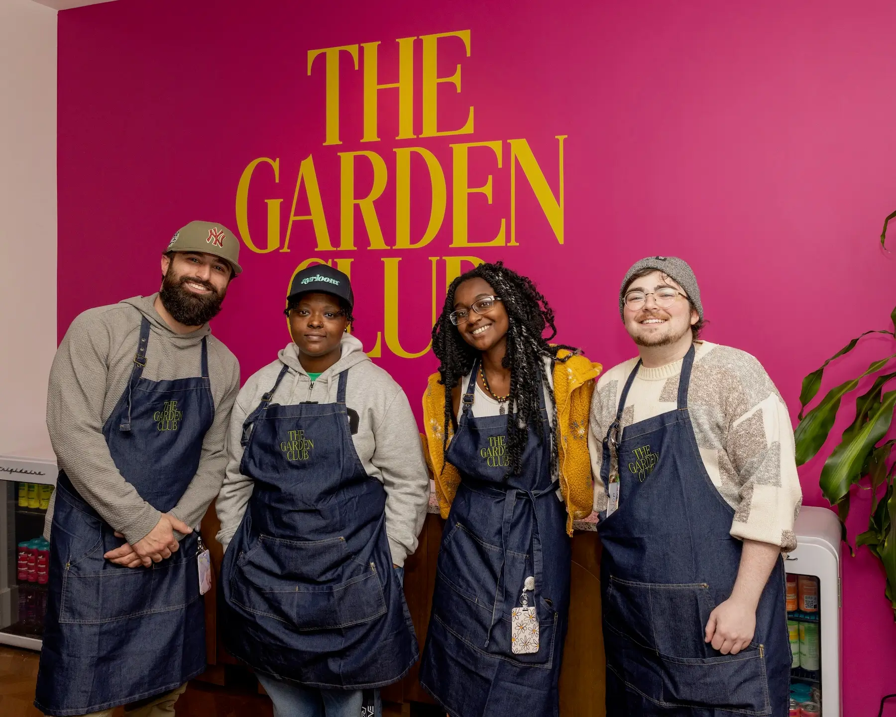 The Garden Club team in front of the brand wordmark wall